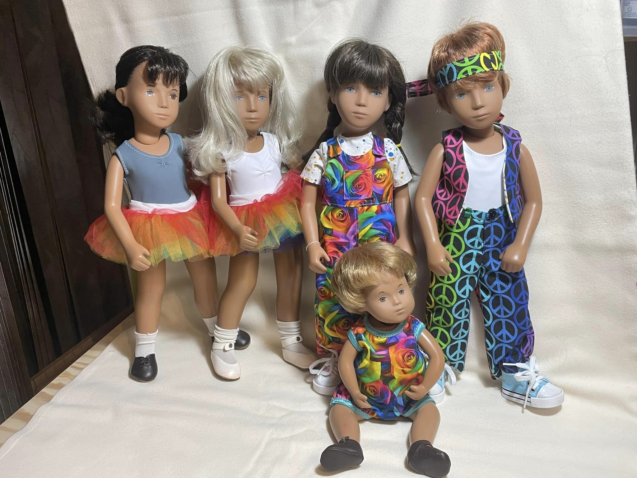 Five Sasha Morgenthaler dolls wearing rainbow-themed outfits